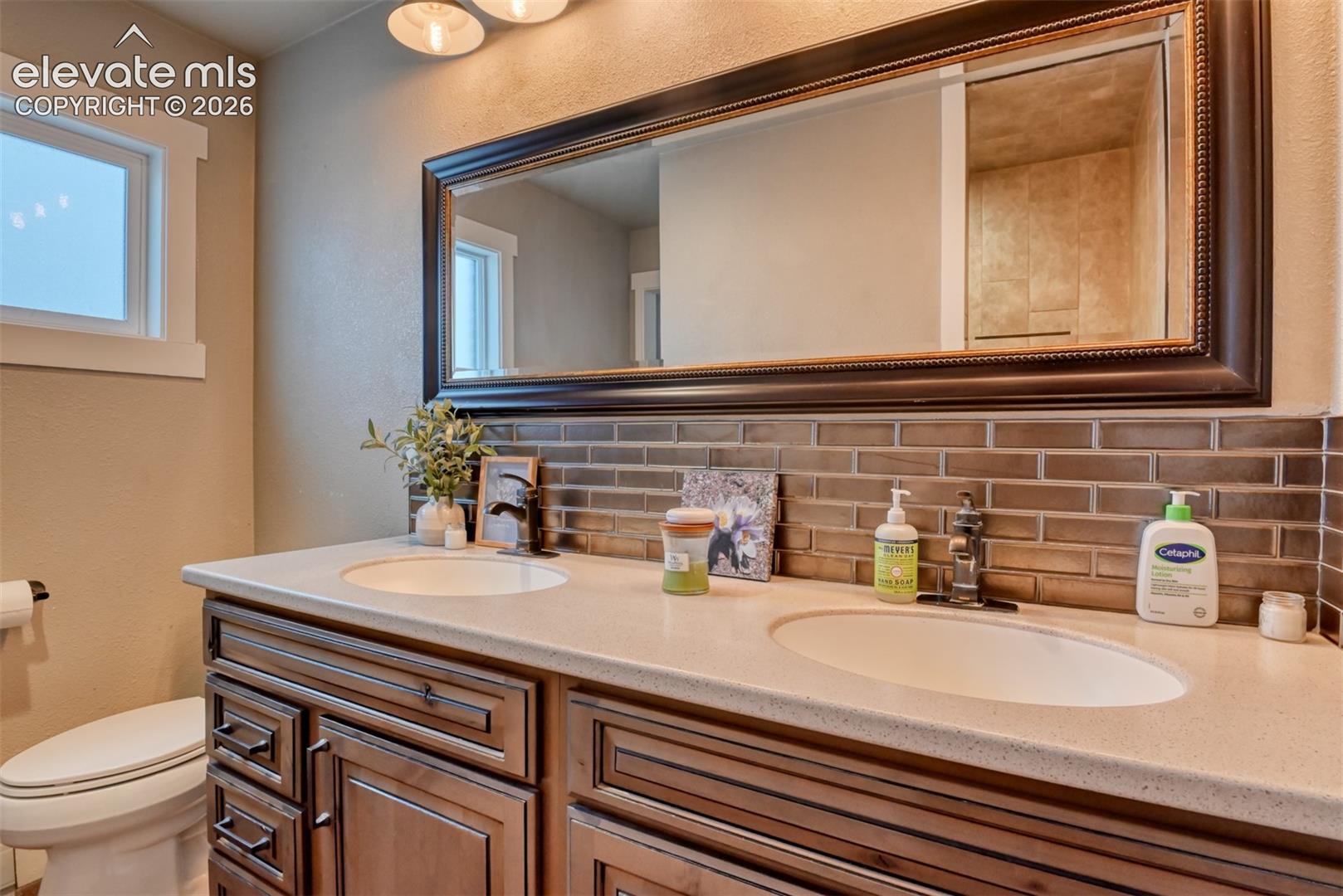 Full bath featuring backsplash, a textured wall, and double vanity