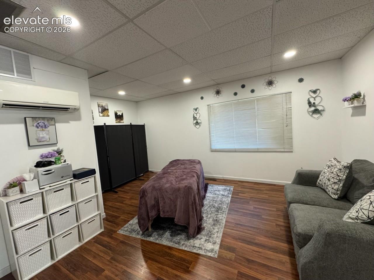 Recessed lighting, wood-finish flooring, drop ceiling, window with blinds, and white walls