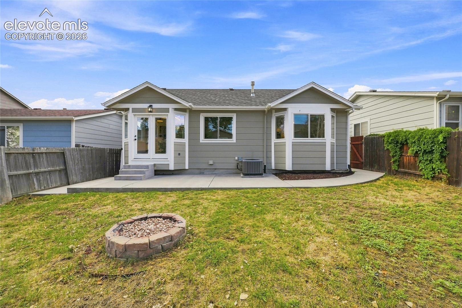 Spacious backyard with a concrete patio, built-in fire pit, and privacy fencing