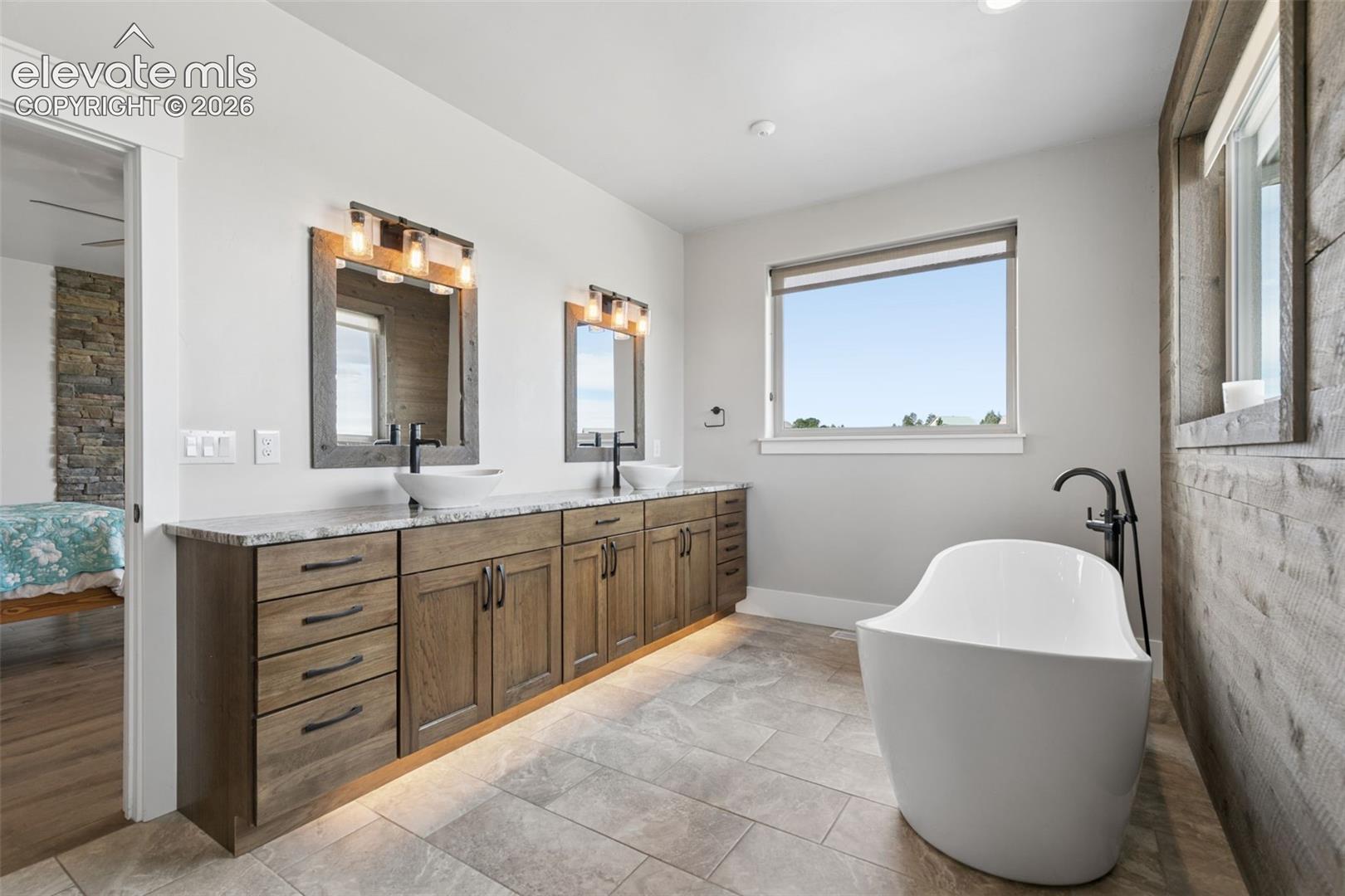 Dual vanity with wood-finish cabinetry, under-cabinet lighting, and stone countertops