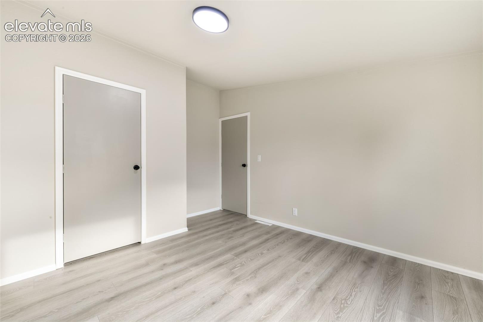 Light gray wood-finish flooring, neutral wall color, and a flush-mount ceiling light