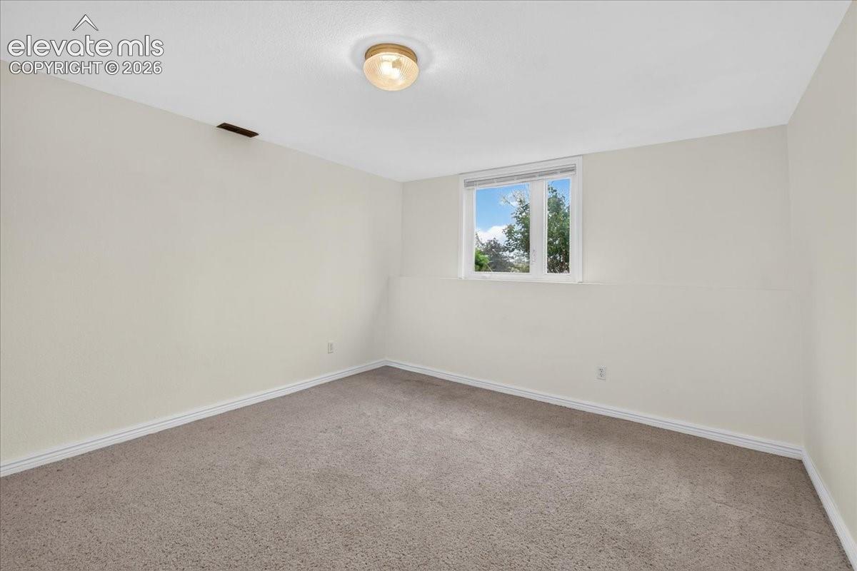 Interior space featuring neutral-toned carpeting, light-colored walls, a single-pane casement window, and a flush-mount dome ceiling light