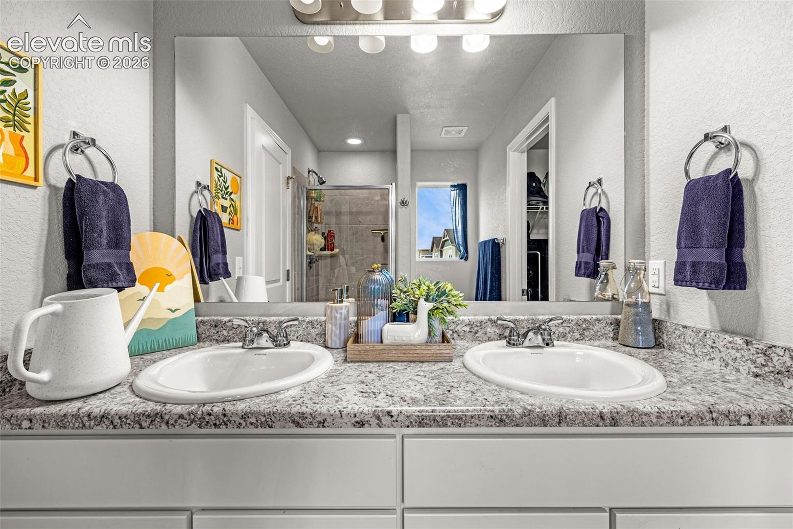 Dual vanity featuring white integrated sinks, speckled countertops, and chrome fixtures