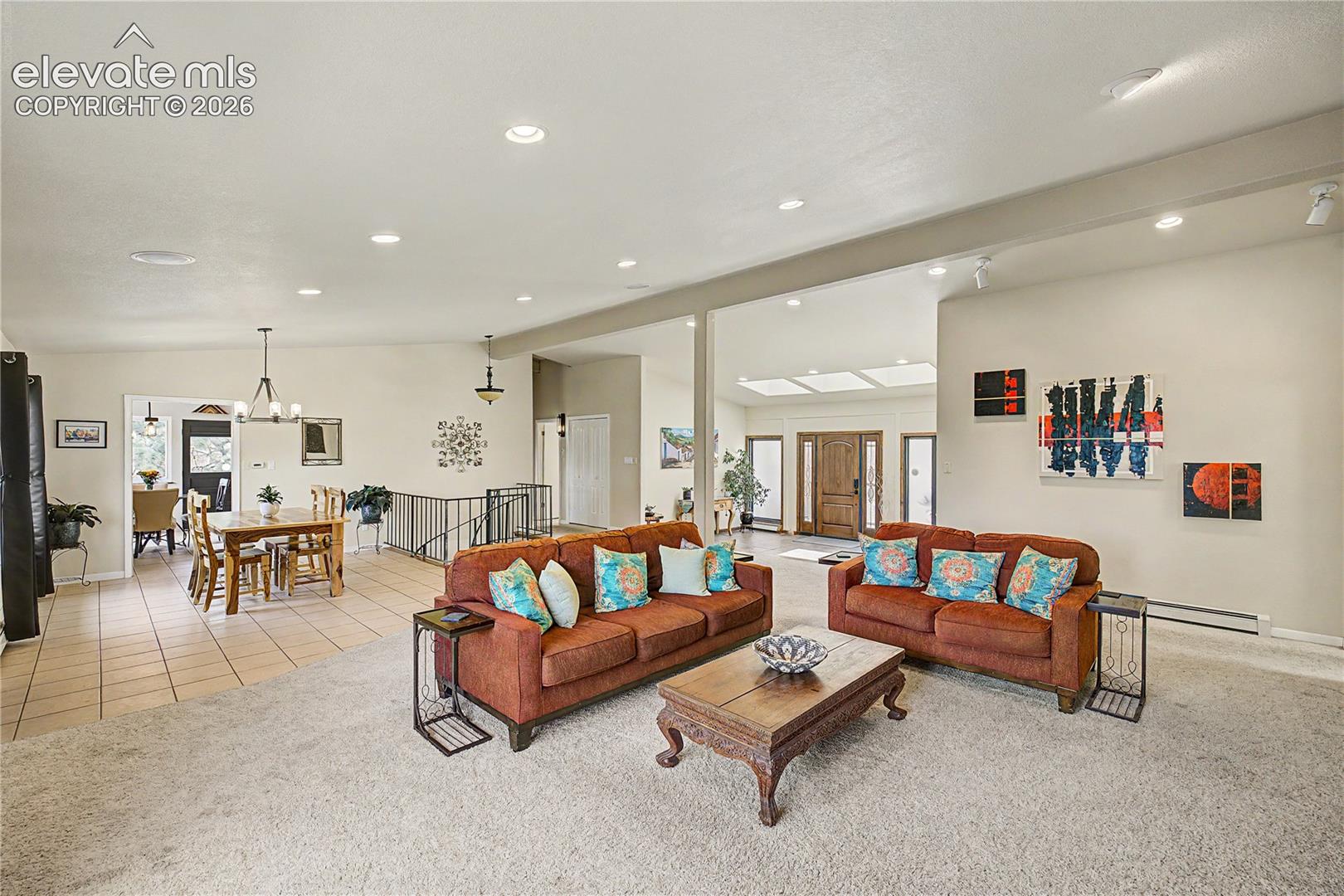 The open living and dining areas flow into one another, separated only by a wrought-iron stair railing that hints at even more living space waiting just below.