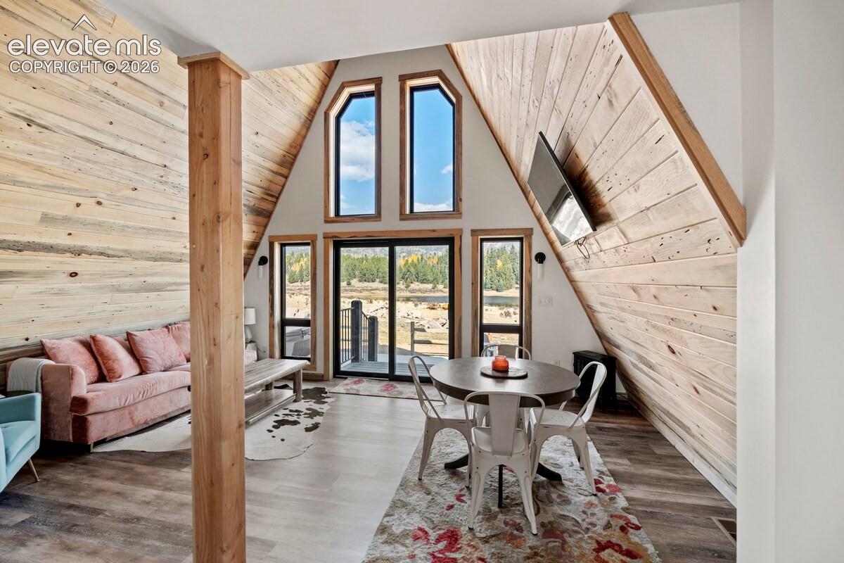 A-frame architecture featuring soaring vaulted ceilings, natural wood-paneled walls, floor-to-ceiling windows, and wood-finish flooring