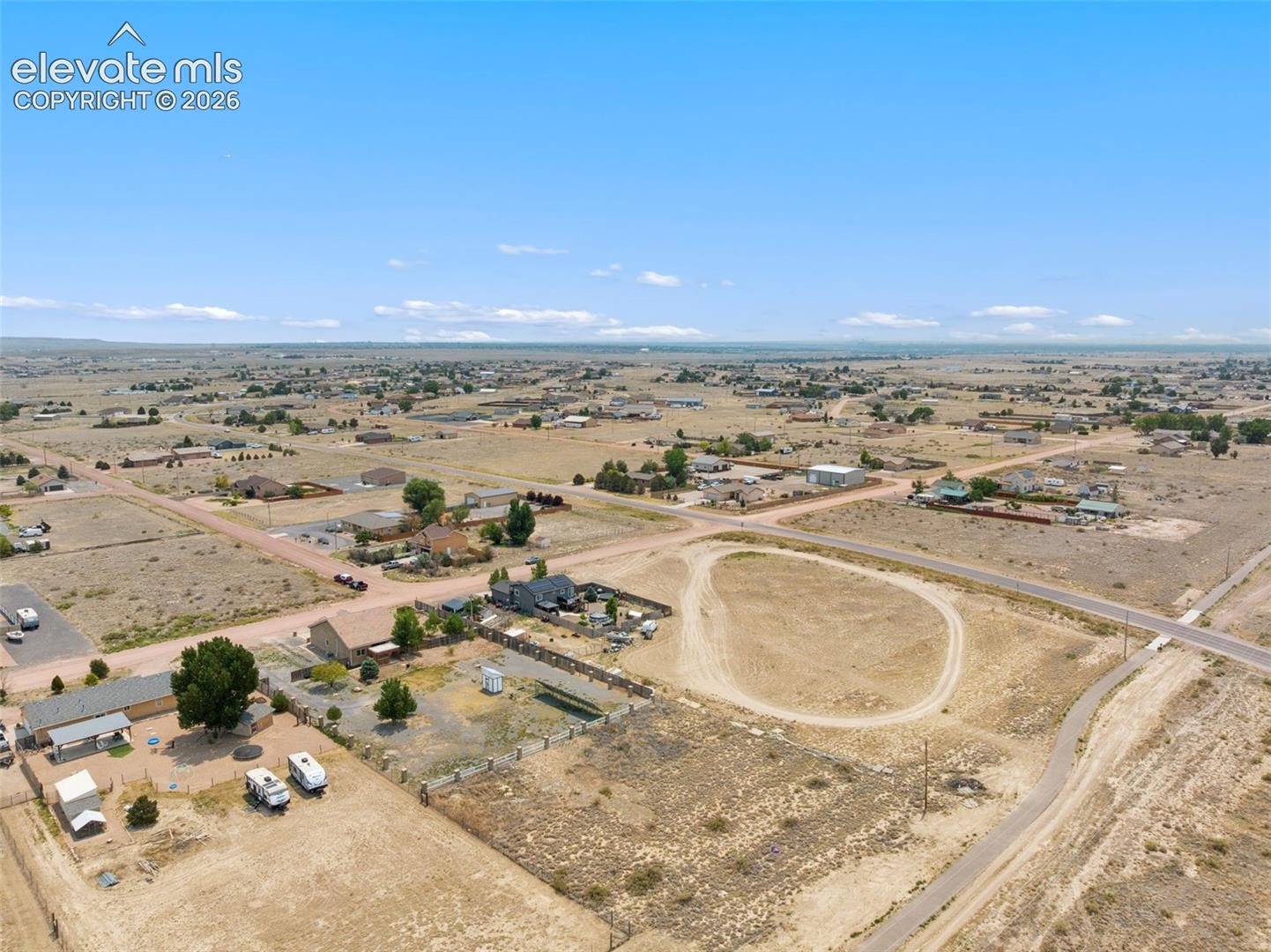 Expansive parcel of land featuring corner lot positioning, cleared terrain, and dirt-surfaced driveway access
