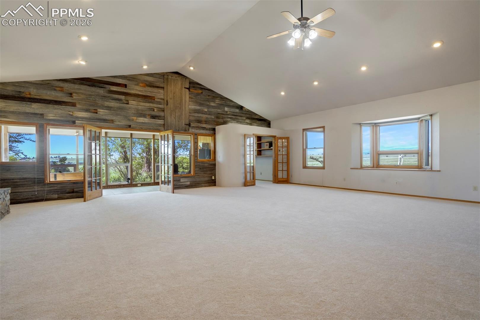 Expansive room featuring a vaulted ceiling with recessed lighting and a ceiling fan