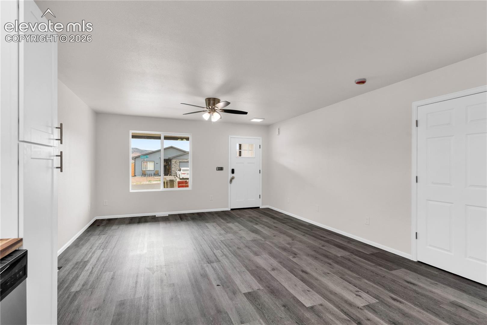 Neutral-toned interior featuring wood-finish flooring, a ceiling fan with integrated lighting, a multi-pane exterior door, and a white six-panel interior door