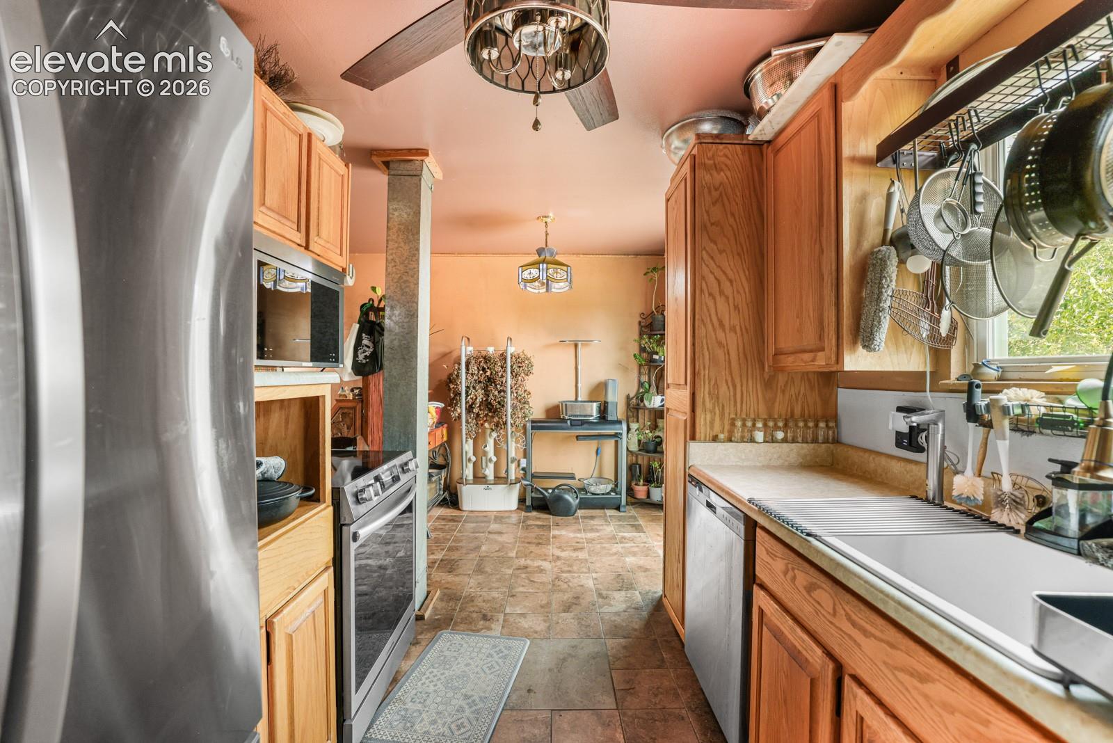 Kitchen featuring wood cabinetry, stainless steel appliances, and a ceiling fan