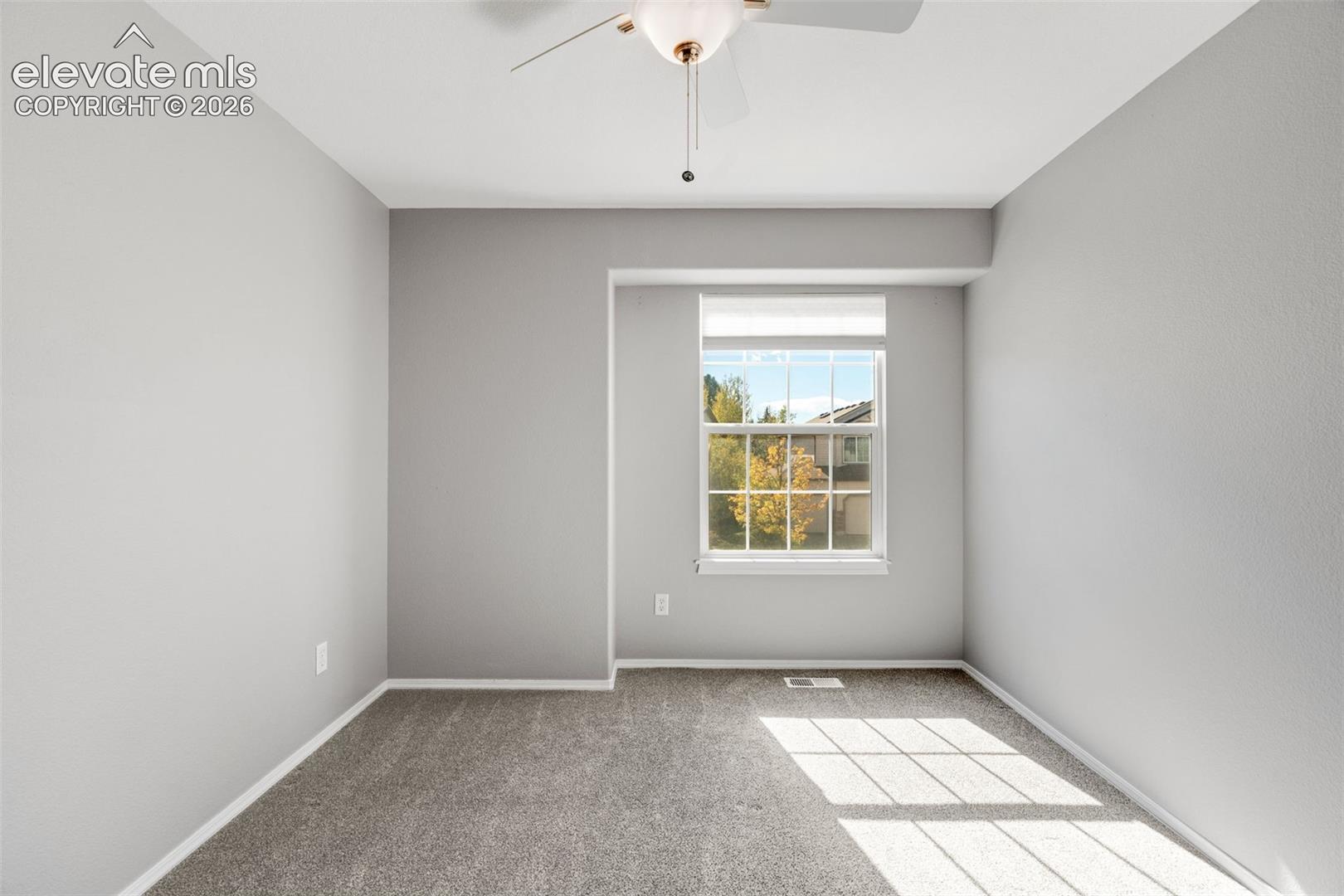 Neutral-toned room featuring wall-to-wall carpeting, a recessed window, and a ceiling-mounted light fixture