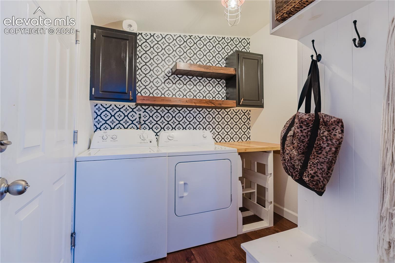 Laundry area featuring patterned tile, dark cabinetry, wood-finish shelving, and a built-in folding counter