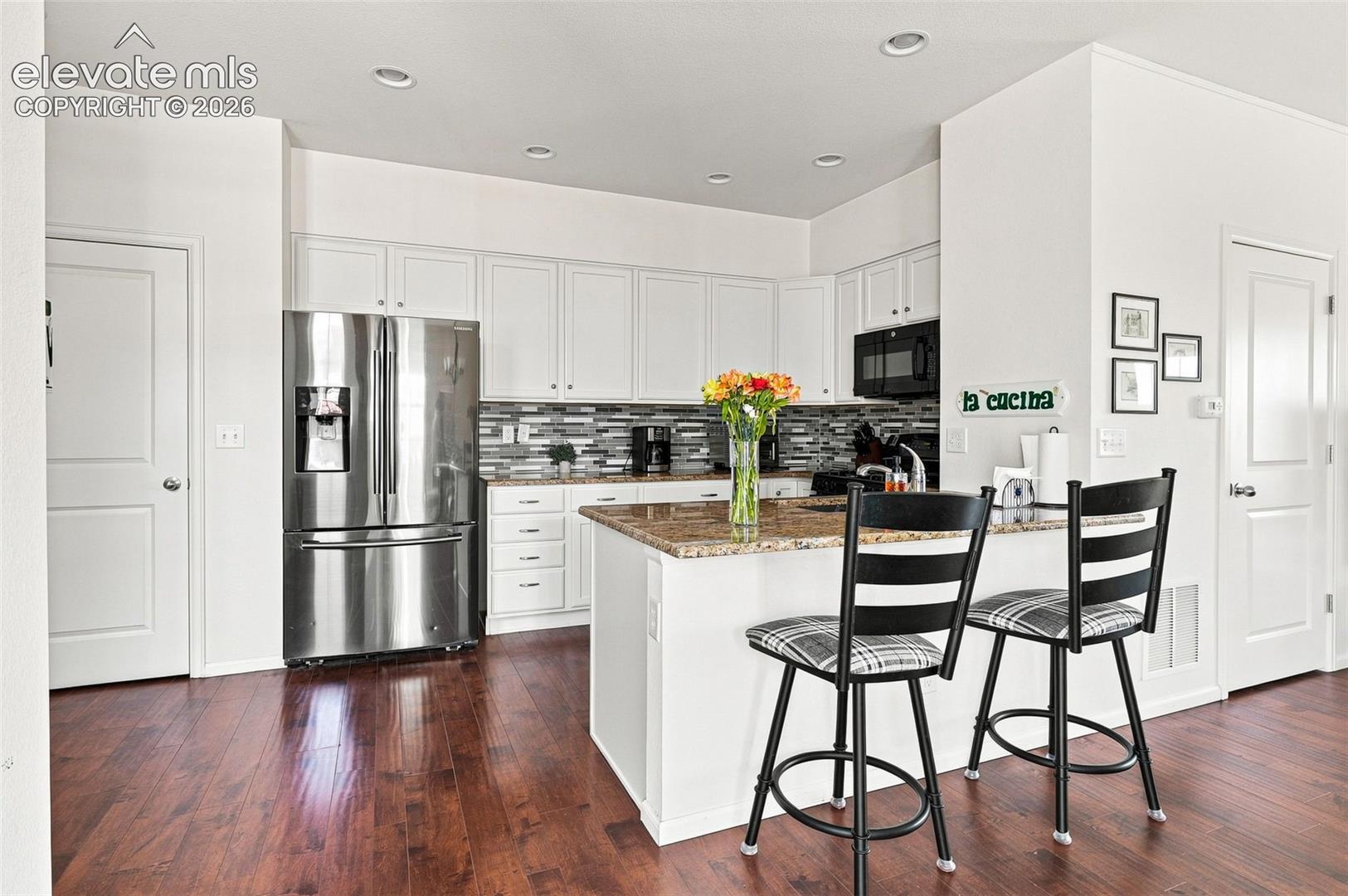 Light and bright adjacent to patio with granite countertops, counter with bar seating and wood floors