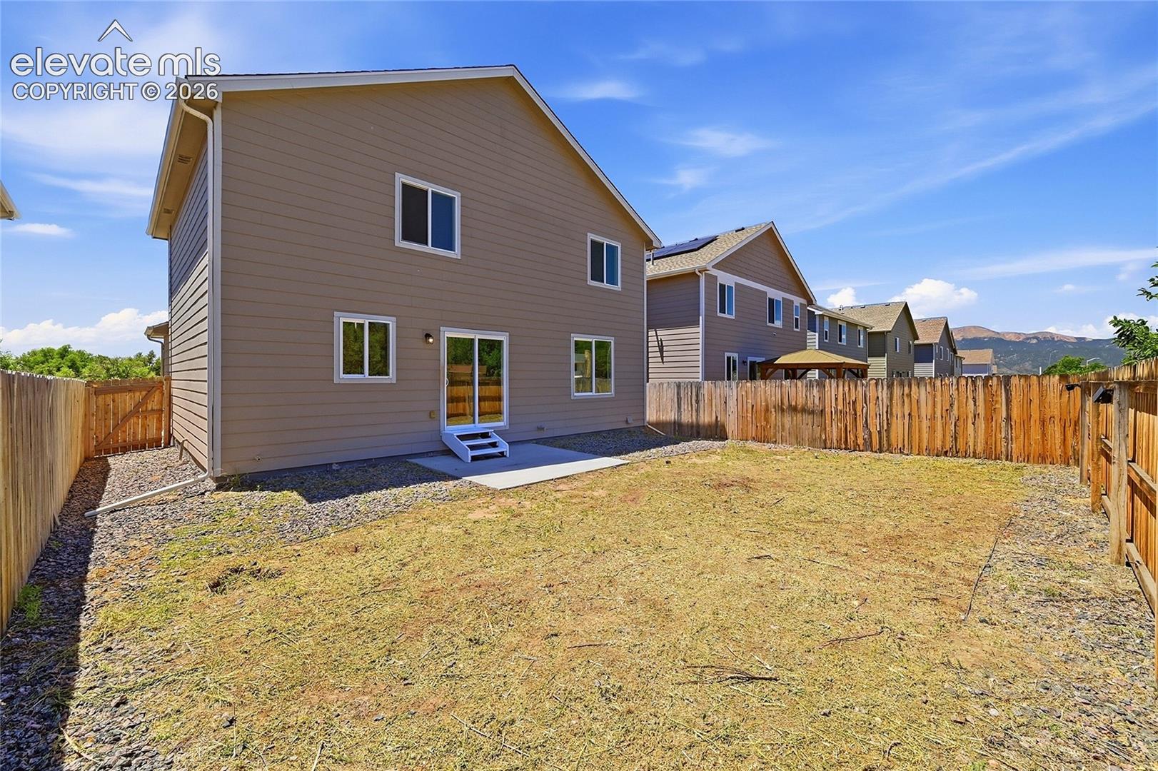 Spacious backyard featuring a full wood privacy fence and a rear patio