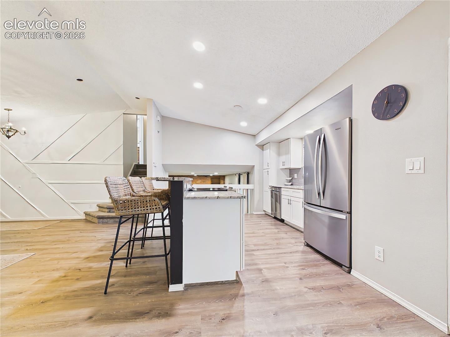 Modern finishes, stainless steel appliances, recessed lighting, and an expansive breakfast bar create a bright and inviting gathering space.