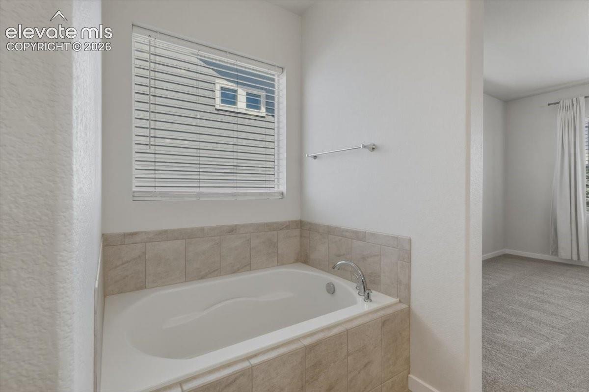 Alcove soaking tub with tile surround and chrome fixtures