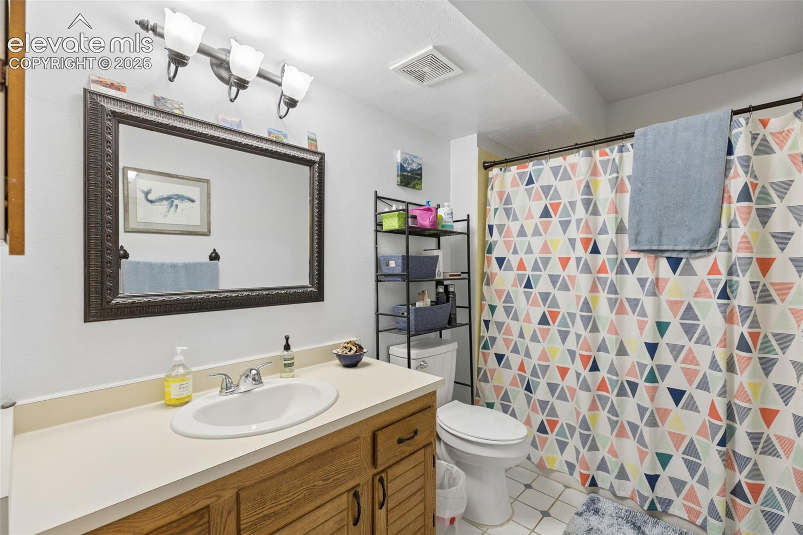 Vanity with integrated sink, wood-finish cabinetry, and a large framed mirror