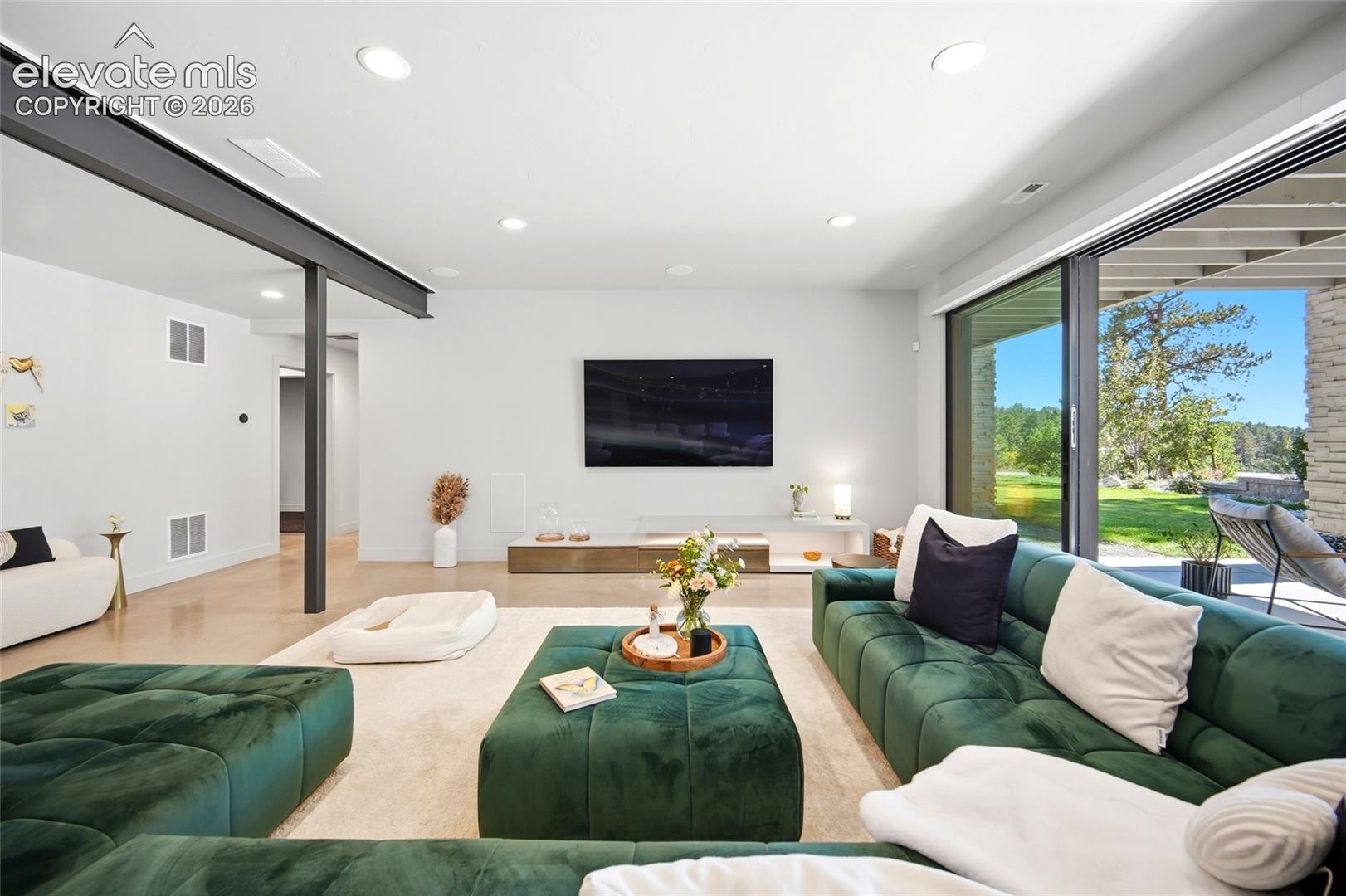 Spacious living area featuring recessed lighting, a structural beam, and expansive sliding glass doors opening to the exterior