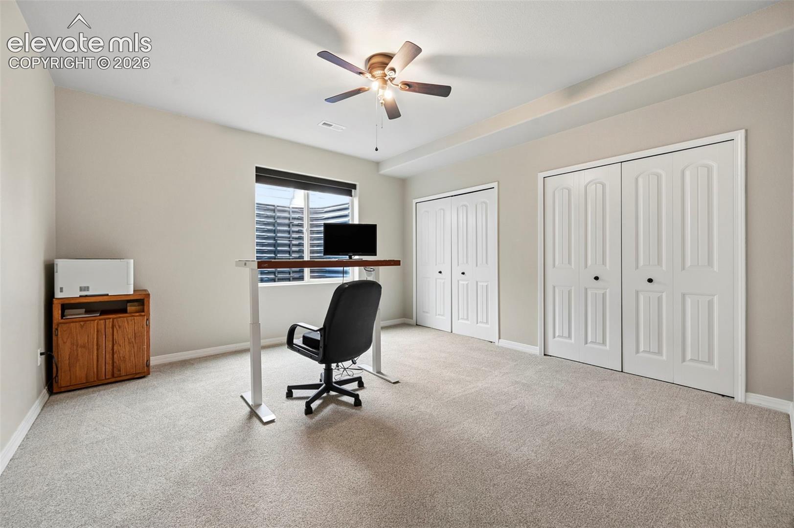 Neutral wall tones, wall-to-wall carpeting, dual closets with panel doors, and a ceiling fan with integrated light fixture