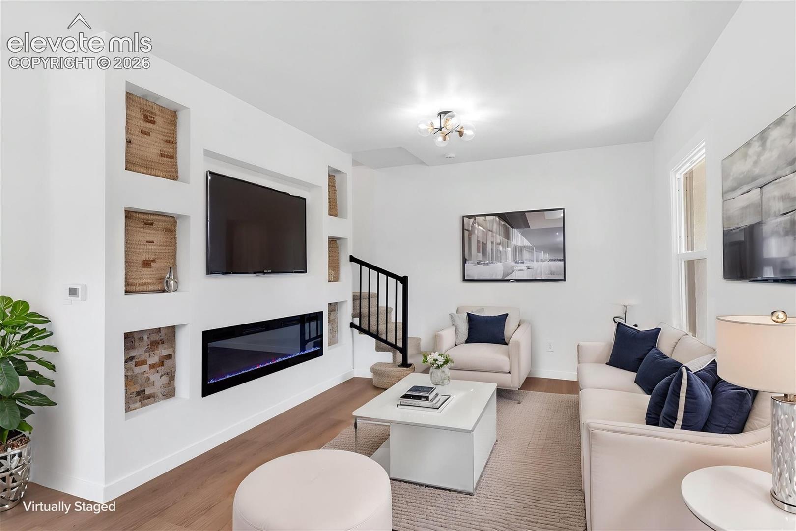 Living area featuring a custom built-in entertainment wall with recessed shelving, a linear electric fireplace, stone-tile accents, and wood-finish flooring