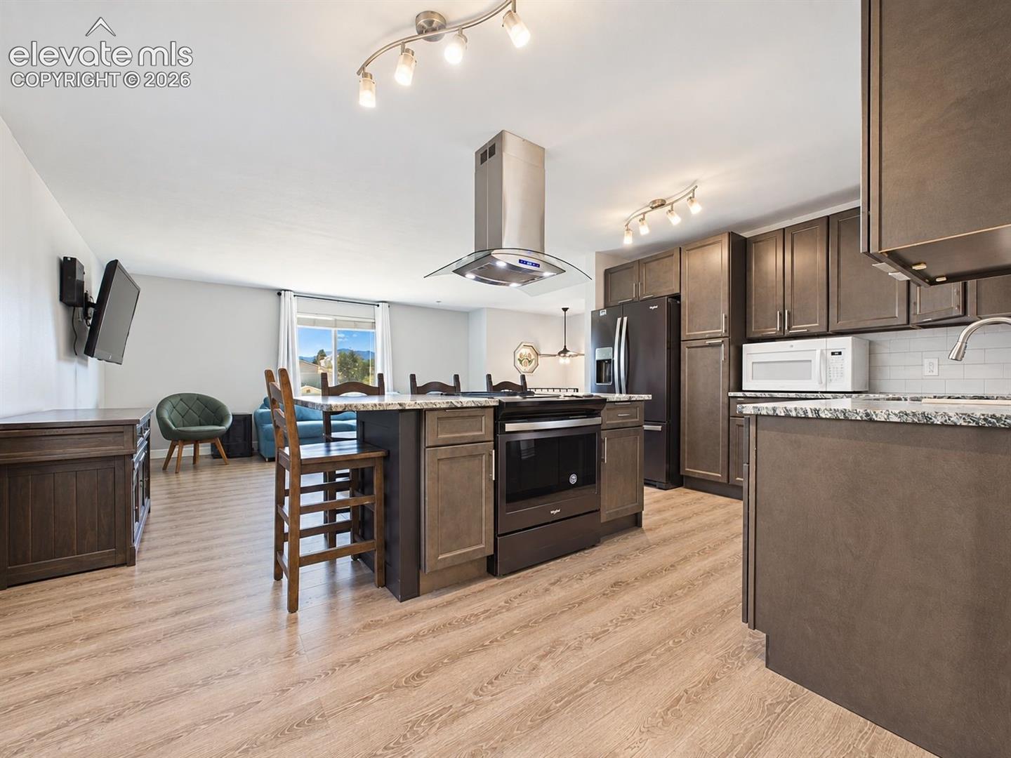 Spacious remodeled kitchen pairs dark cabinetry with contrasting countertops, modern lighting, and a large center island that provides both workspace and casual seating.
