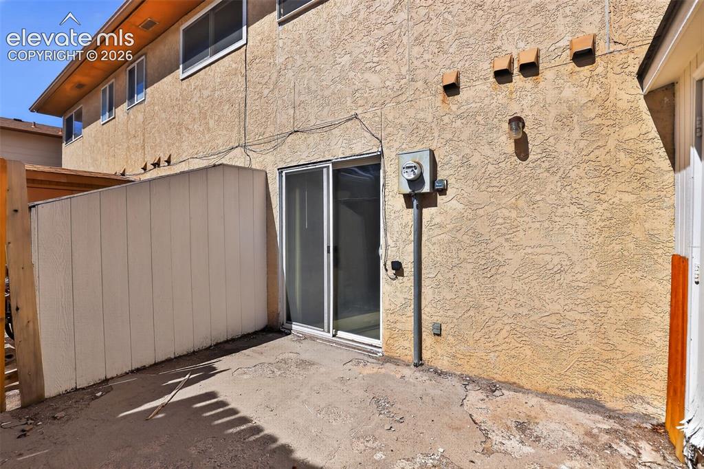 Ground-level patio area featuring a concrete surface and stucco exterior