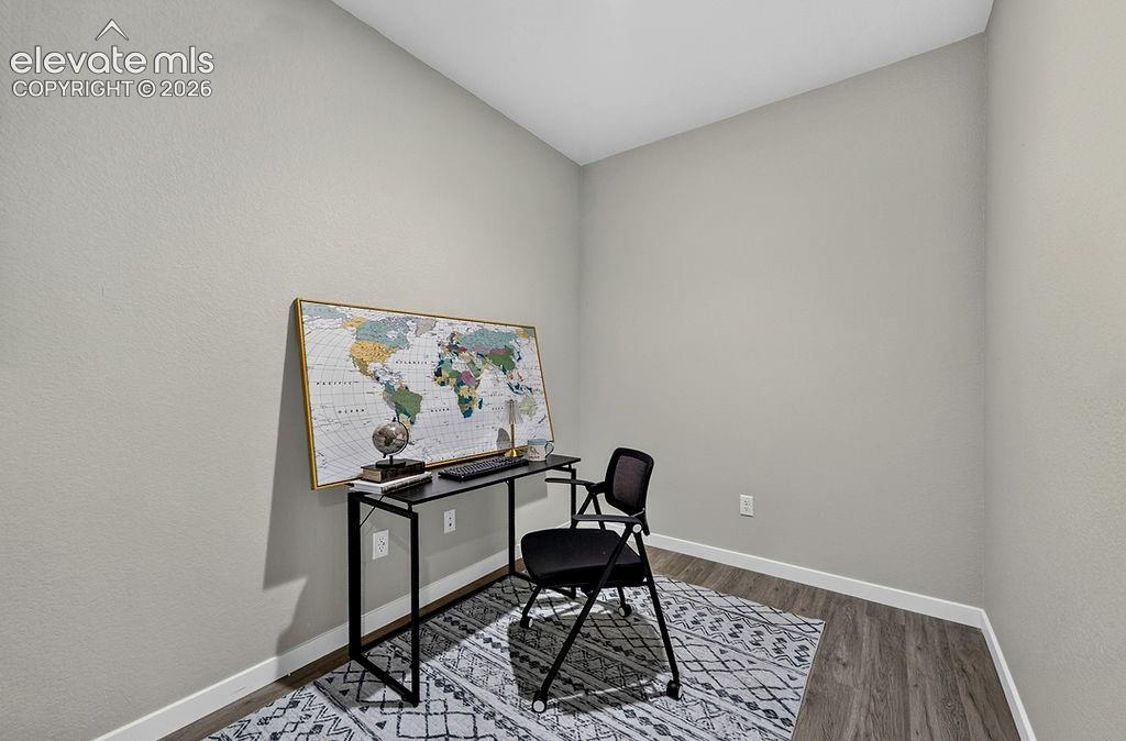 Room featuring light gray walls, white baseboards, and wood-finish flooring