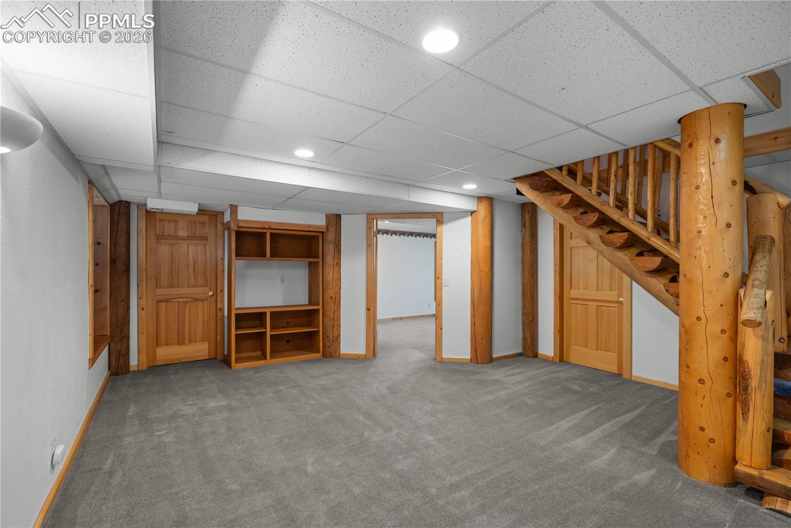 Finished below grade area with carpet floors, stairs, a drop ceiling, and recessed lighting