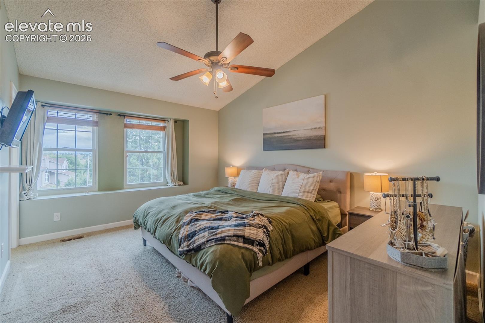 Vaulted ceiling with a ceiling fan, new windows with window seat, and carpeted flooring