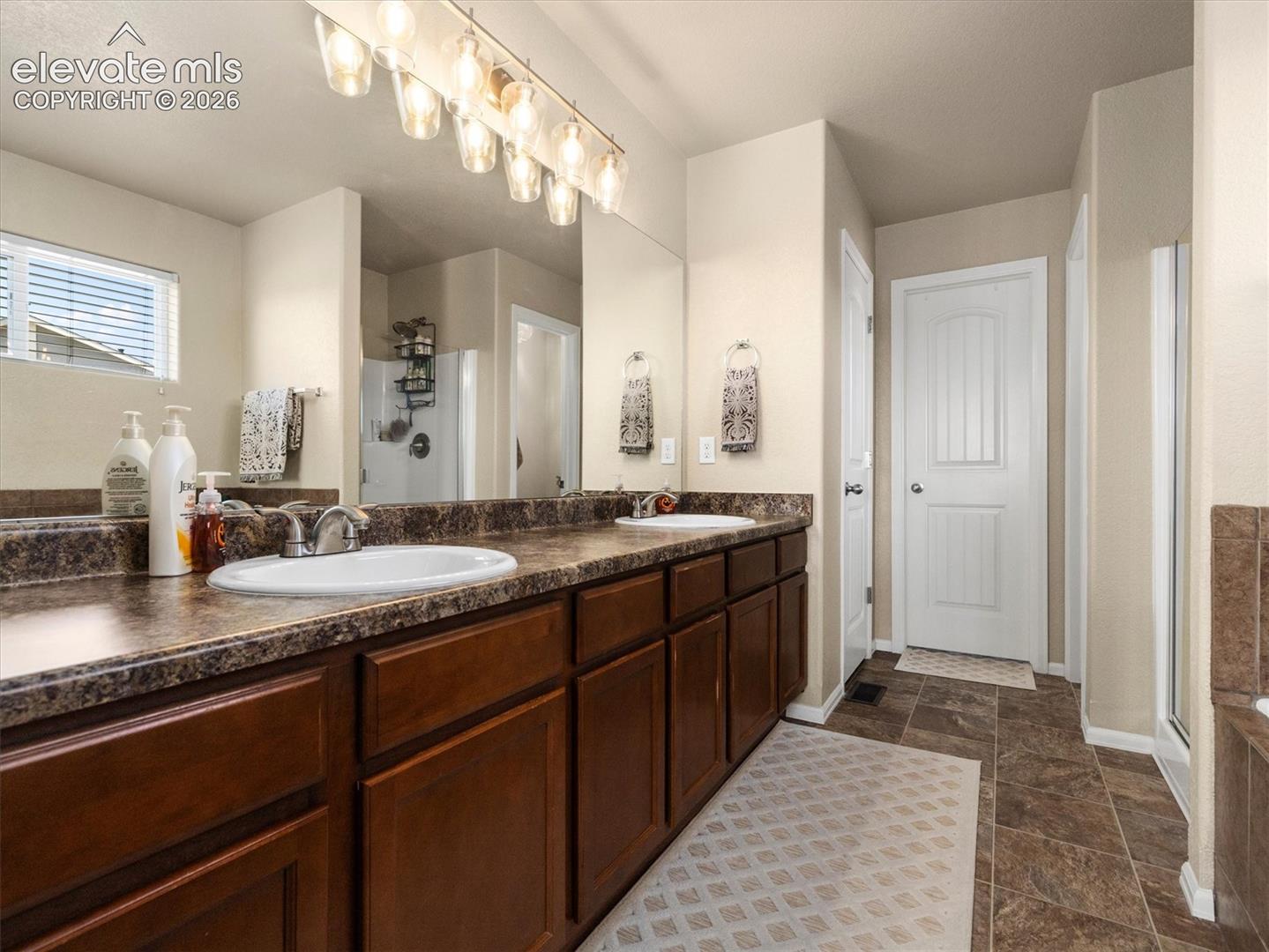Double vanity with integrated sinks, dark wood-finish cabinetry, and a patterned countertop