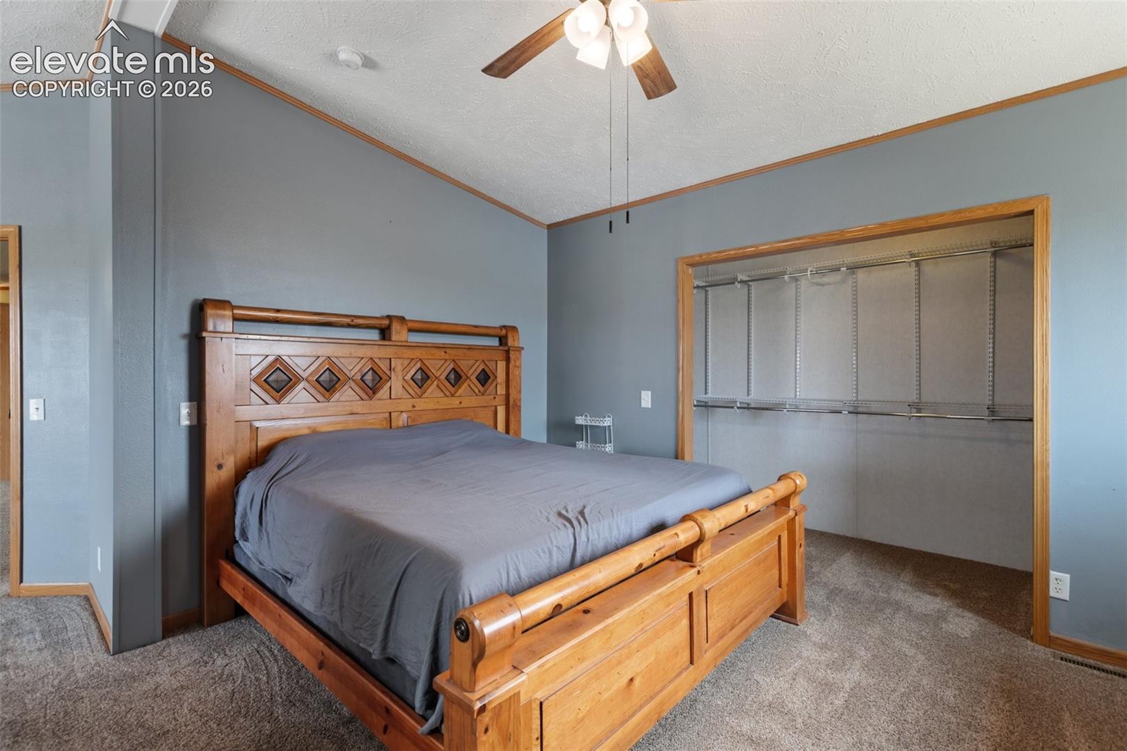 Carpeted room with a vaulted ceiling and a ceiling fan