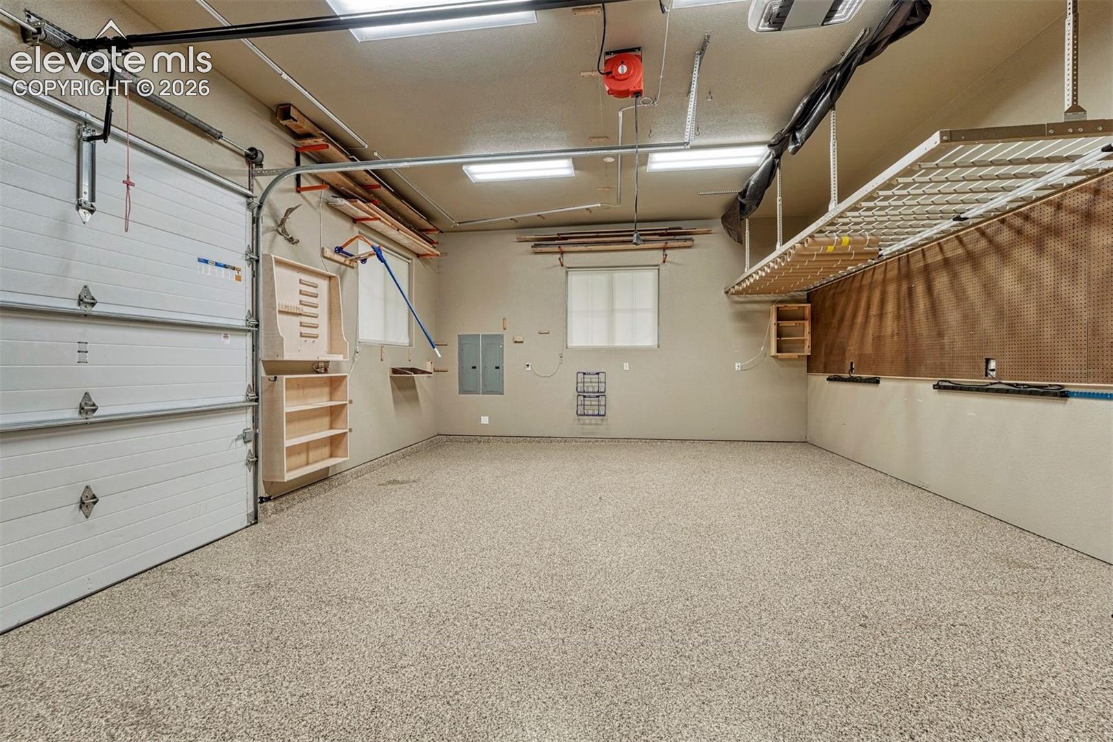 Garage featuring a durable epoxy floor finish, overhead garage door, built-in shelving, and overhead storage racks