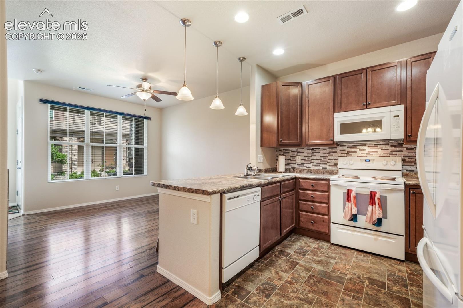 Kitchen with wood-finish cabinetry, white appliances, and a mosaic tile backsplash