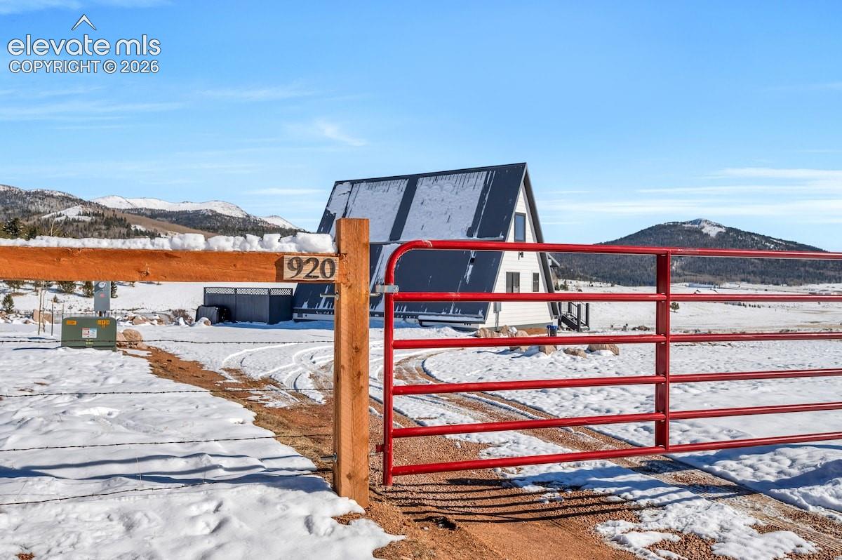 A-frame structure featuring a metal roof, metal gate entrance, and mountain backdrop