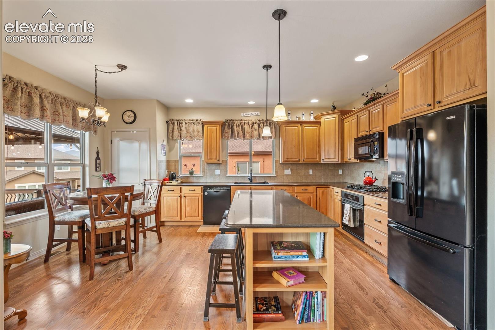 Kitchen featuring wood-finish flooring, natural wood cabinetry, a central island with countertop seating, and recessed lighting