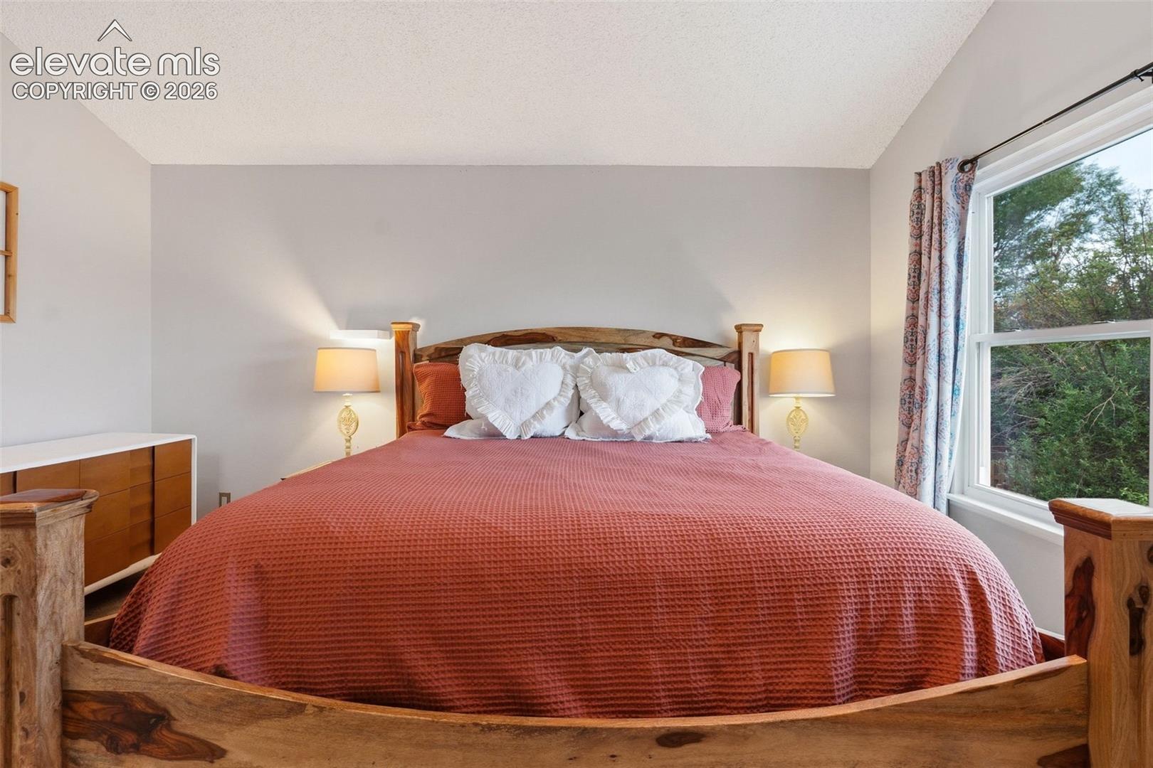 Wood-finish bed frame, expansive window, and a built-in wood-finish dresser