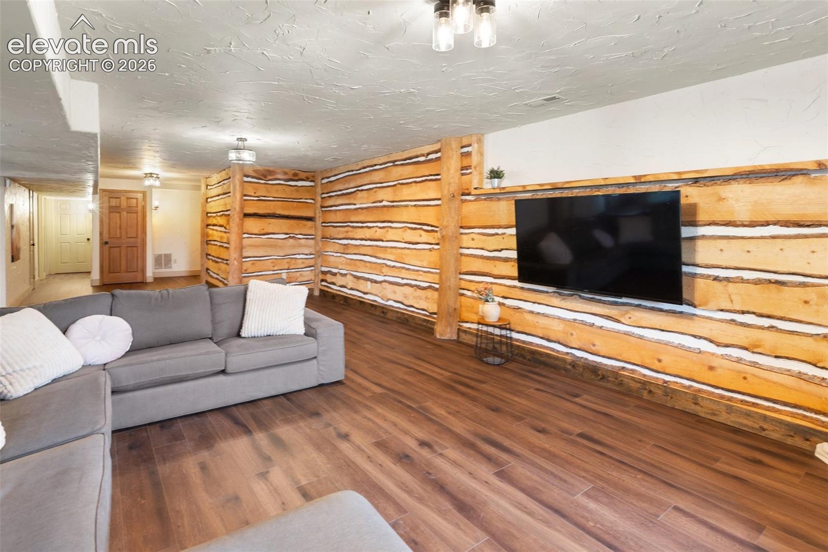 Interior space featuring natural wood-log wall paneling, wood-finish flooring, and recessed ceiling lighting
