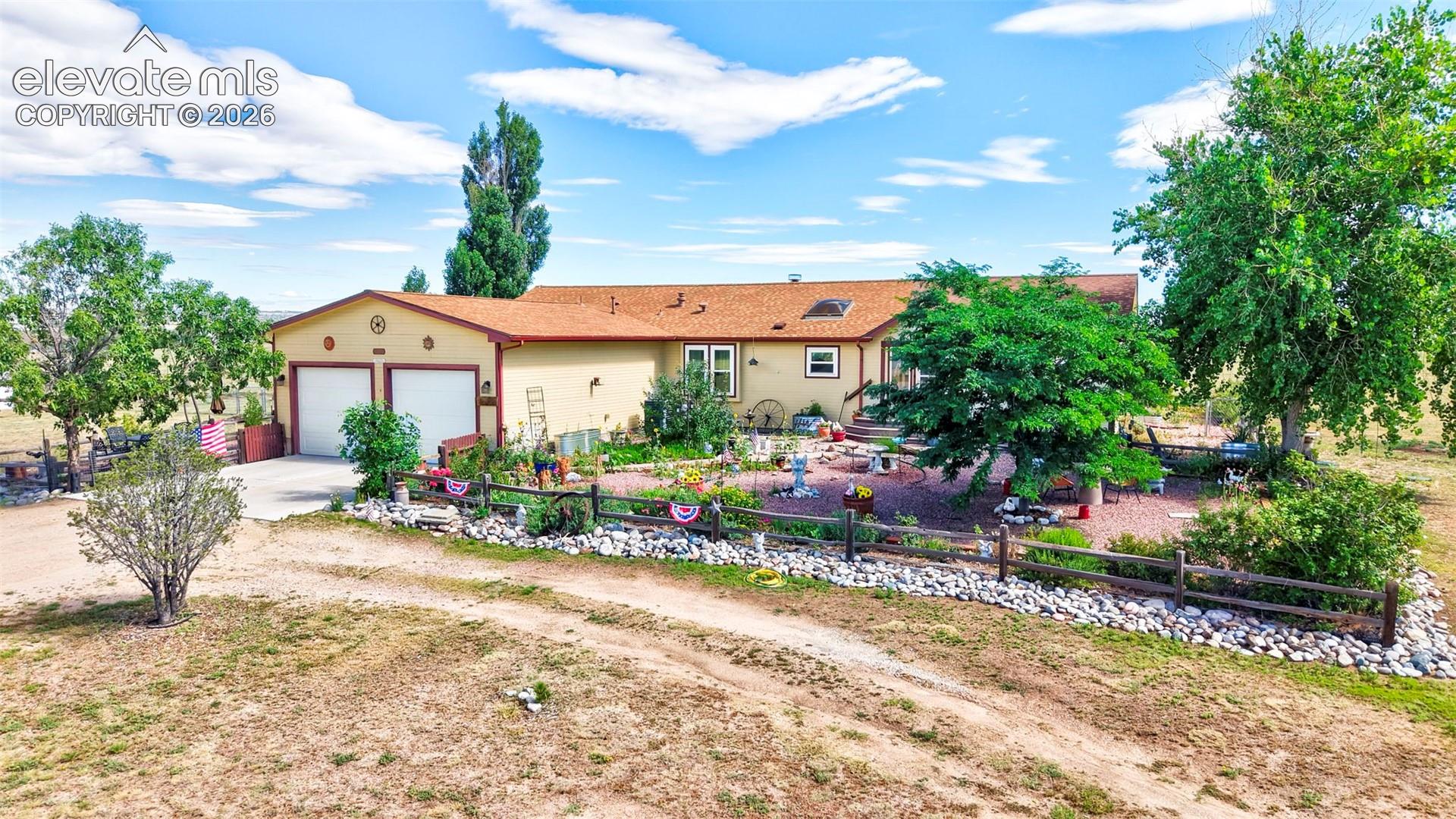 Ranch-style residence featuring a two-car garage, earth-tone exterior, and a terracotta-colored roof