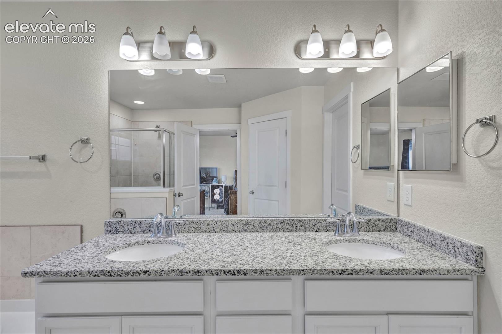 Double vanity with integrated sinks, speckled countertop, and chrome fixtures