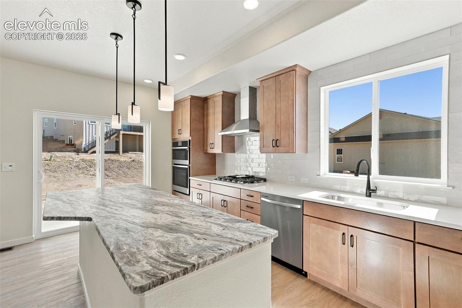The Kitchen features stainless steel appliances, light maple cabinets with pecan stain, a large kitchen island with quartz countertop, and LVP flooring.