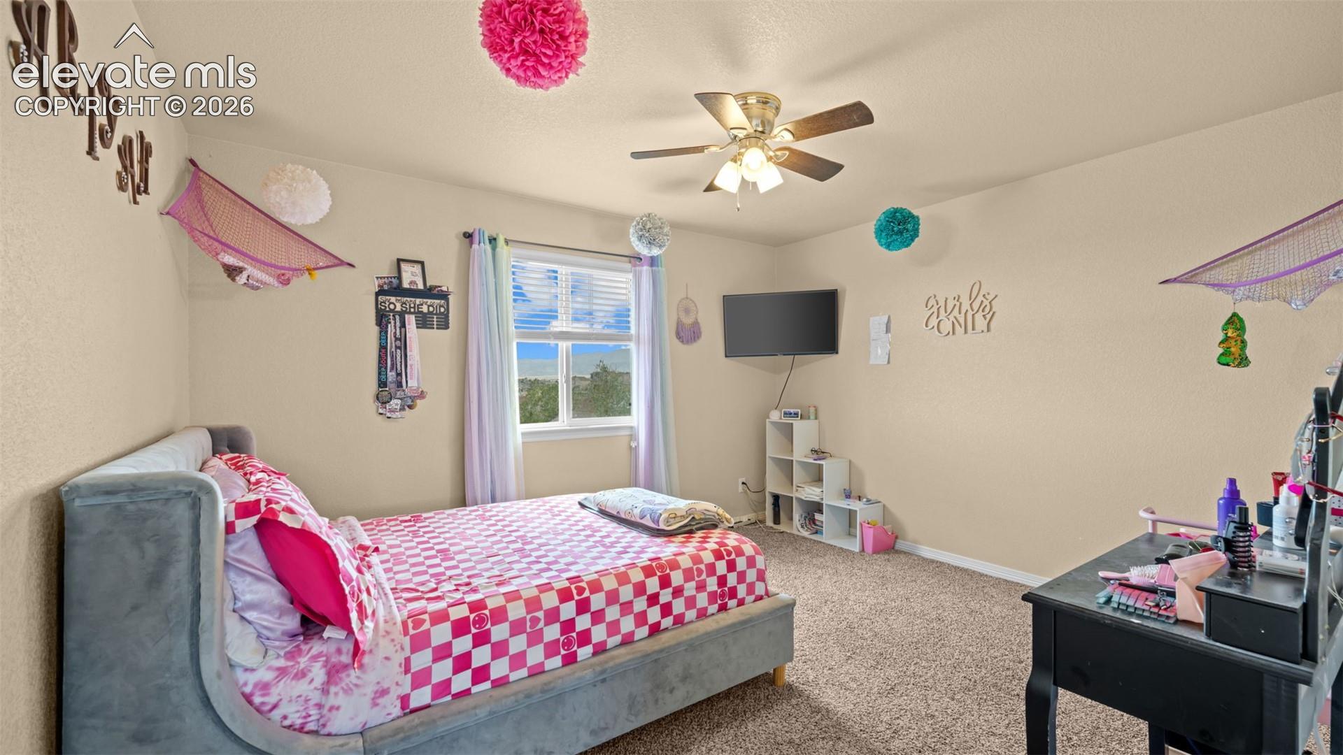 Carpeted room featuring a ceiling fan with integrated lighting, a window with blinds and drapes, and neutral-toned walls