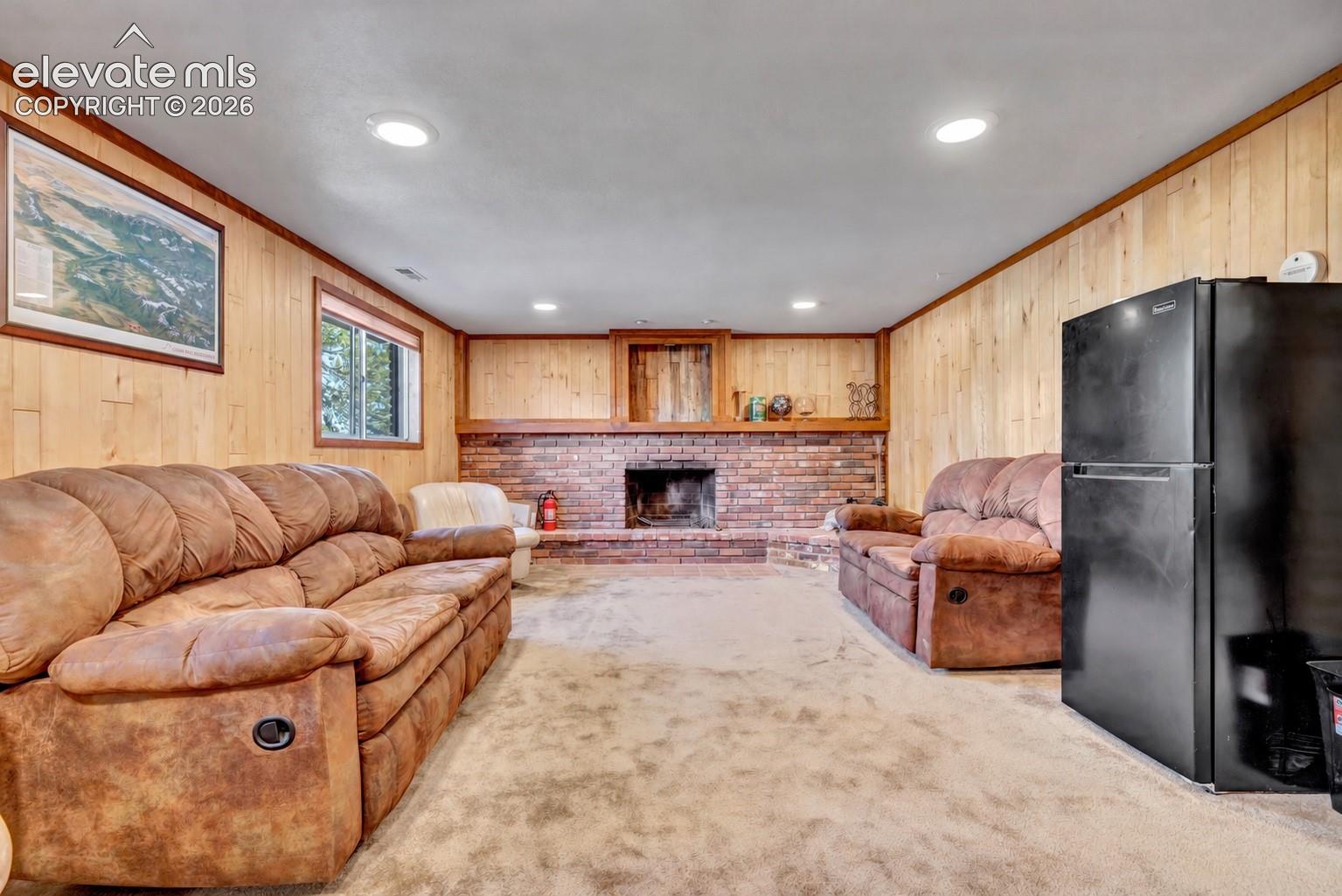 Brick fireplace with a wood mantle, wood paneling, recessed lighting, and a double-pane window