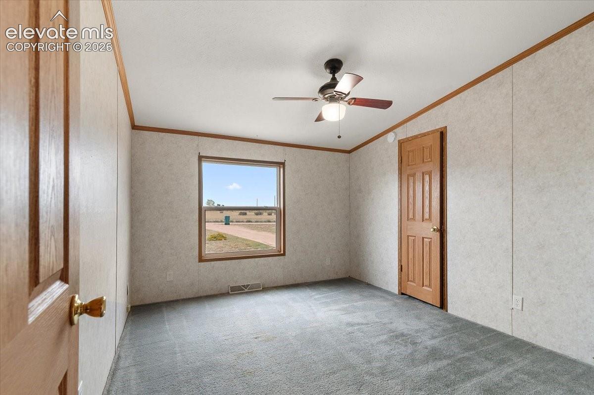 Wall-to-wall carpeting, window with wood-finish trim, wood-finish interior doors, ceiling fan with light fixture, wood-finish crown molding