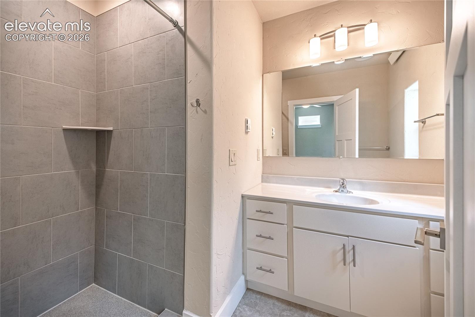 Contemporary bathroom featuring a spacious vanity with white cabinetry, a single basin sink, and a large mirror