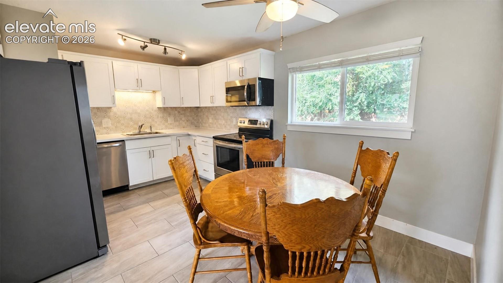 Kitchen featuring white cabinetry, stainless steel appliances, a tile backsplash, and LVP flooring