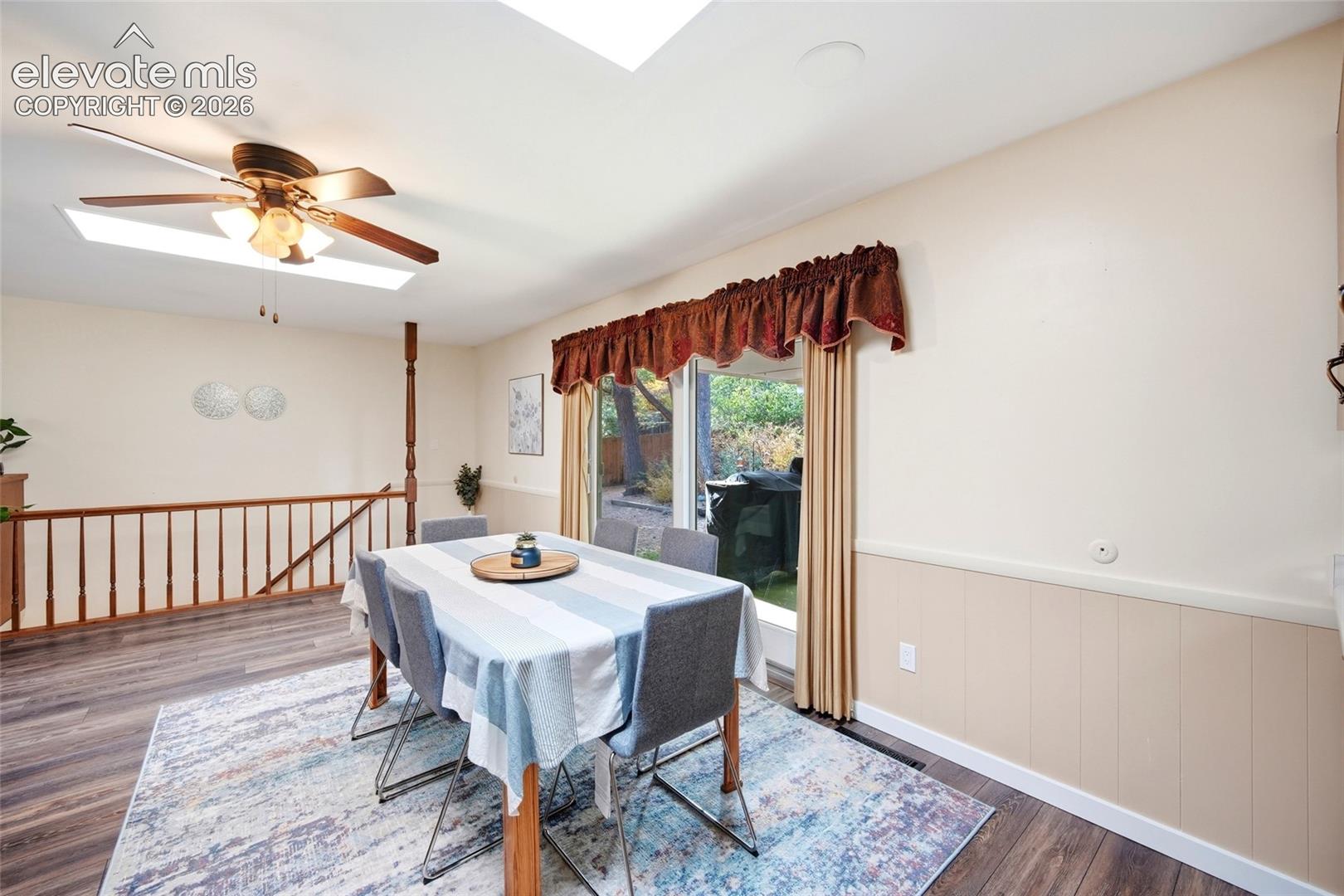 Wood-finish flooring, skylight, ceiling fan with light fixture, and wooden balustrade railing