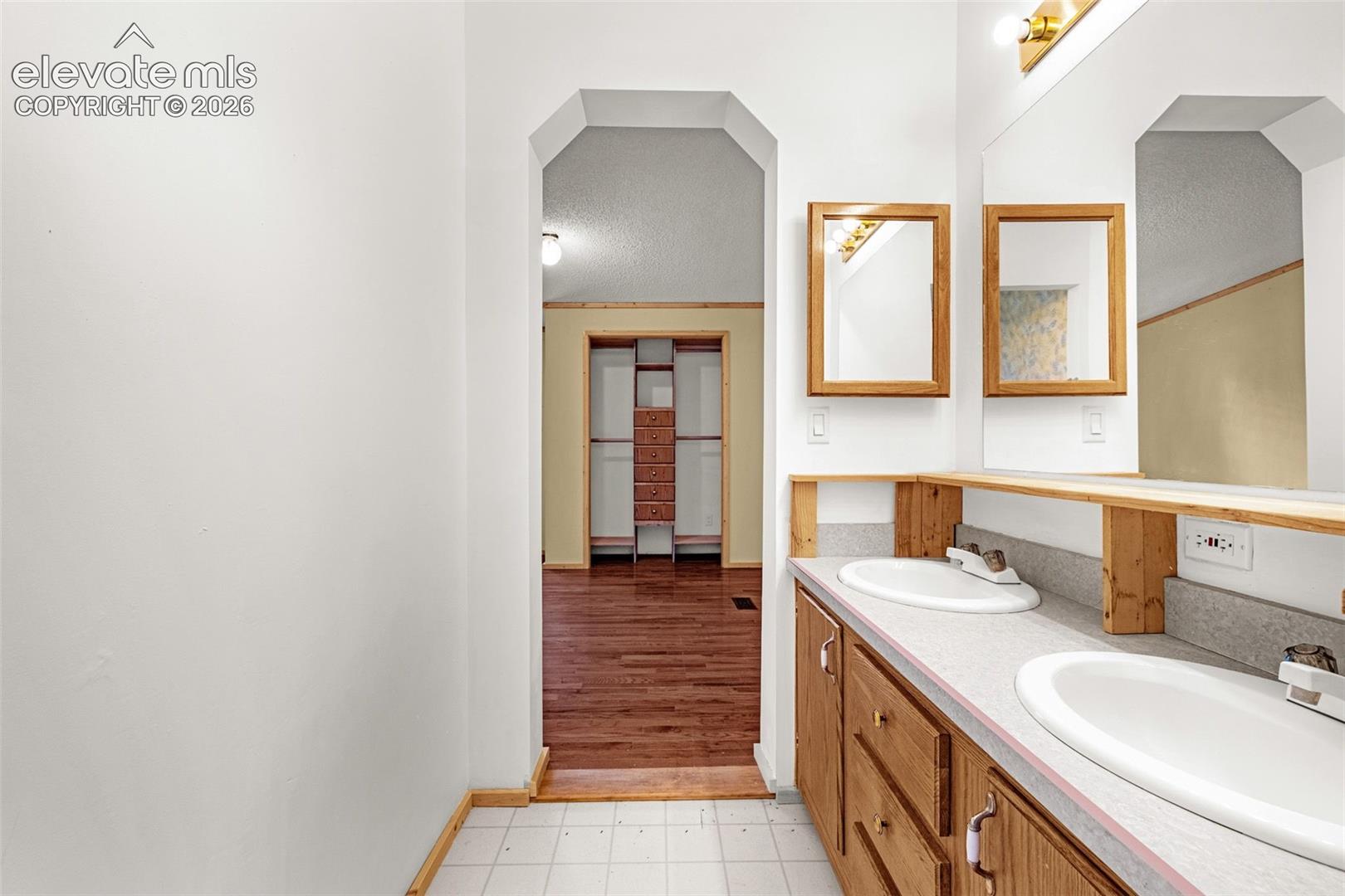 Double vanity with integrated sinks, wood-finish cabinetry, and framed mirrors