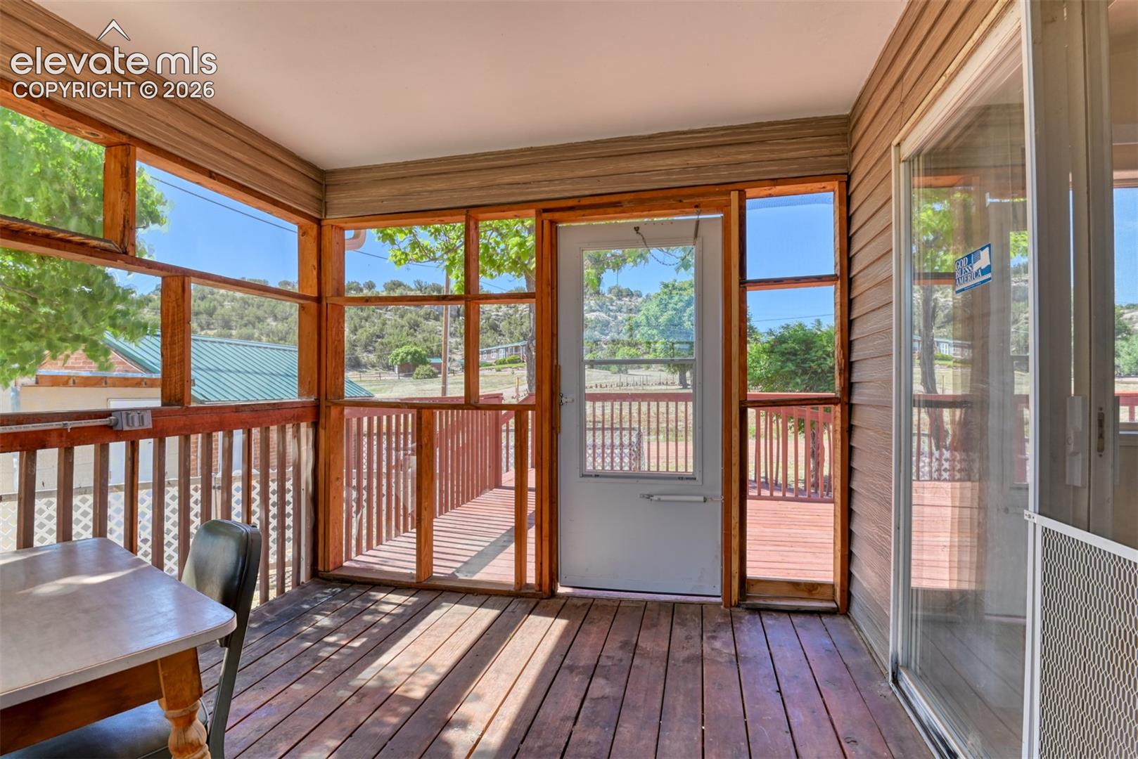Enclosed porch featuring wood-finish flooring, extensive screen wall panels, wood-frame window surrounds, and a glass-paneled exterior door