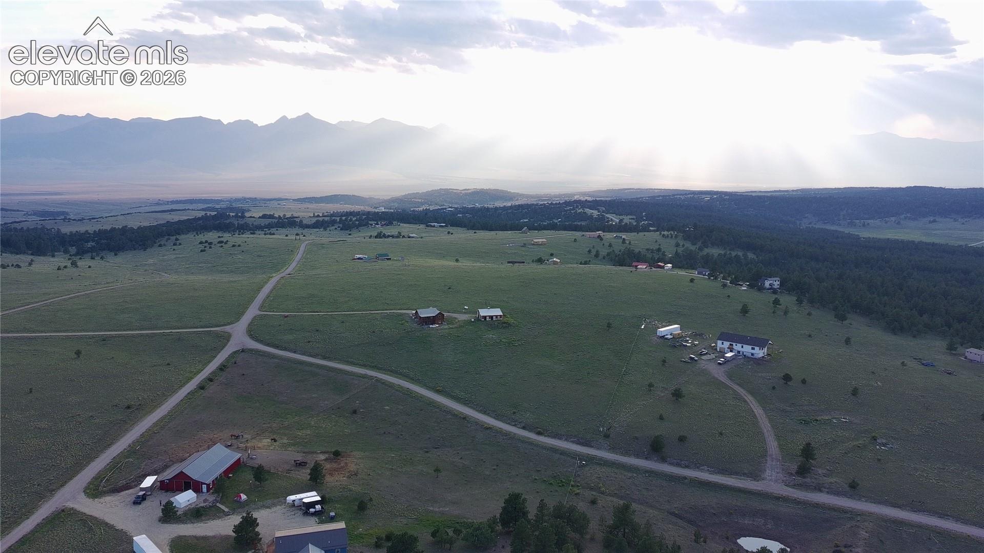 Expansive green landscape with distant mountain ranges and scattered residential structures