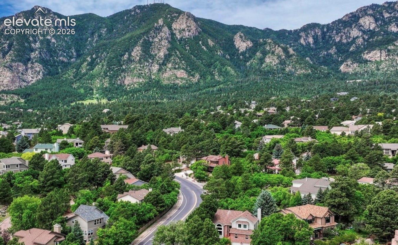 Aerial view with established trees, winding asphalt thoroughfare, and Cheyanne mountain range backdrop