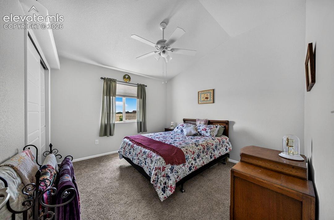 Inviting BR #2 room featuring a vaulted ceiling with a ceiling fan, carpet flooring, and a window with exterior views